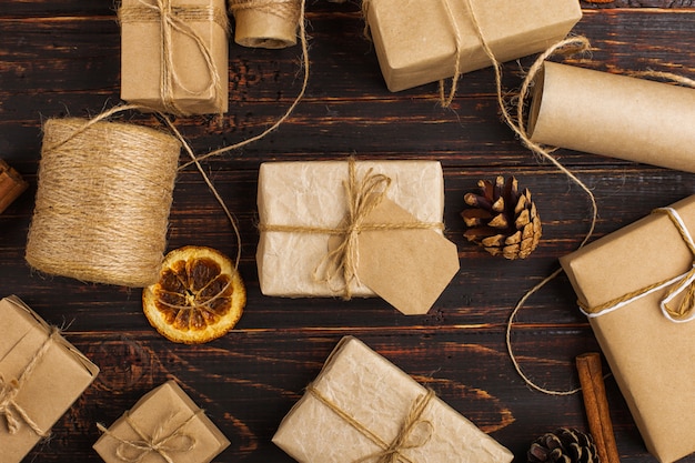 Presente de papel ofício com laranja seca, canela, pinhas, anis em uma mesa de madeira.