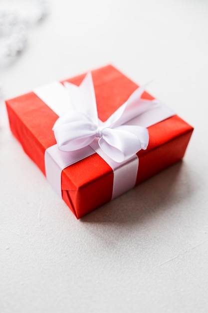 Presente elegante para mulheres lindas em fundo branco fechado caixa de presente vermelha embrulhada de fita e um arco surpresa agradável para aniversário ano novo natal dia dos namorados e outros feriados