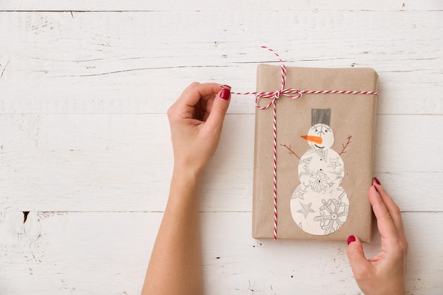 Presente feito à mão lindamente embrulhado. Menina segurando um presente com o desenho infantil de um boneco de neve