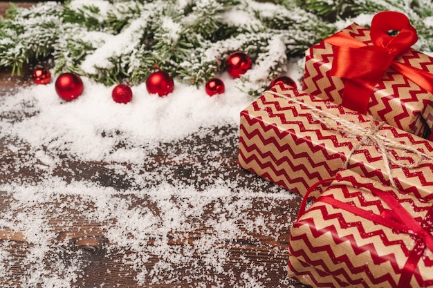 Presente festivo com arco close-up em fundo de madeira com neve