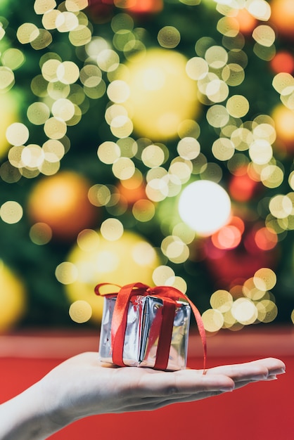 Presente na mão com luz de bokeh de natal