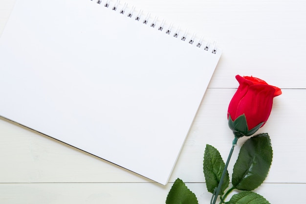 Presente presente com flor rosa vermelha e notebook na mesa de madeira