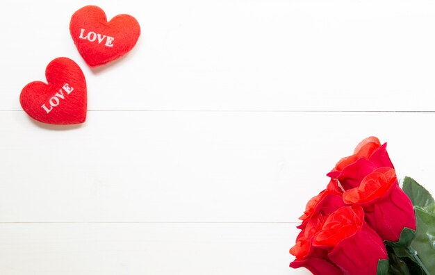 Presente regalo con forma de corazón y flor rosa roja en mesa de madera