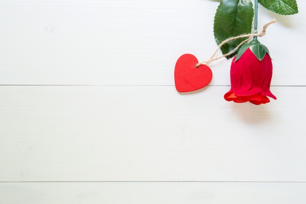 Presente regalo con forma de corazón y flor rosa roja en mesa de madera