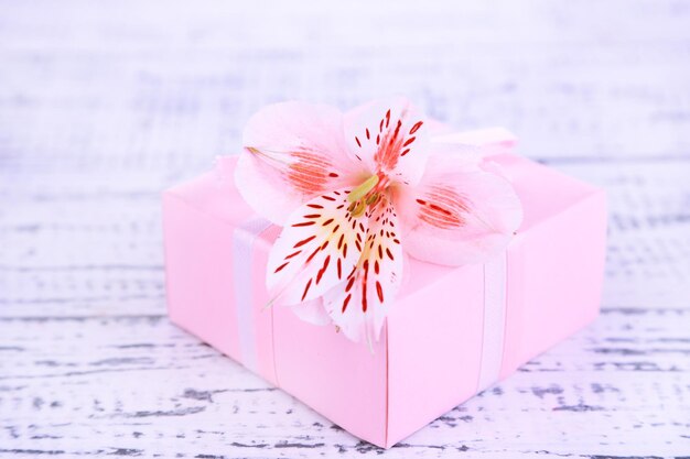 Presente rosa com laço e flor em close-up de mesa de madeira