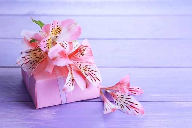 Presente rosa com laço e flor em close-up de mesa de madeira