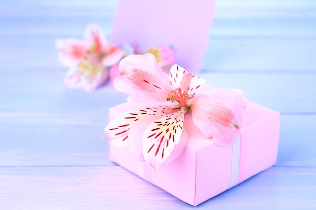 Presente rosa com laço e flor em close-up de mesa de madeira