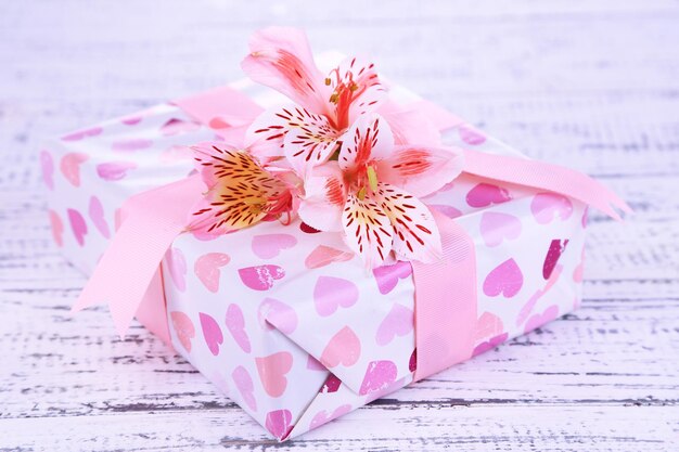 Foto presente rosa com laço e flor em close-up de mesa de madeira