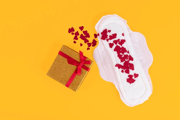 Presente surpresa Muitos pequenos símbolos de corações vermelhos do ciclo menstrual em um absorvente feminino