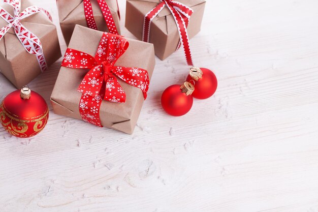 Presentes artesanais de natal com fita vermelha em fundo branco de madeira