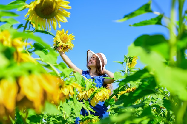 Presentes da natureza criança feliz infância usa chapéu de palha de verão criança no campo de flores amarelas menina adolescente no campo de girassol conceito de férias de verão rica colheita e agricultura