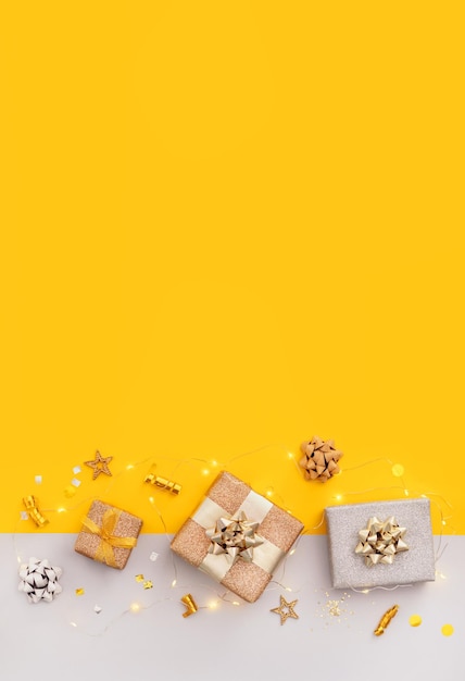 Presentes de decoração de composição luzes de natal em uma vista superior de fundo amarelo brilhante com lugar para texto