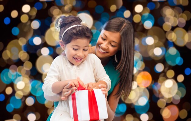 Foto presentes de férias e pessoas conceito feliz mãe e filho menina com caixa de presentes sobre luzes de fundo