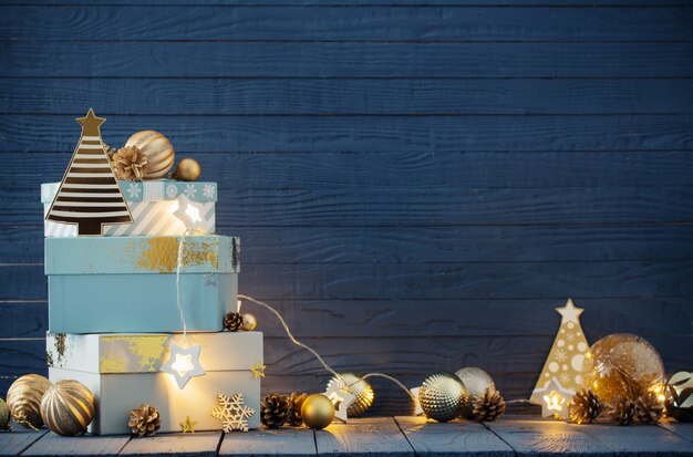 Presentes de Natal com enfeites dourados sobre fundo azul de madeira