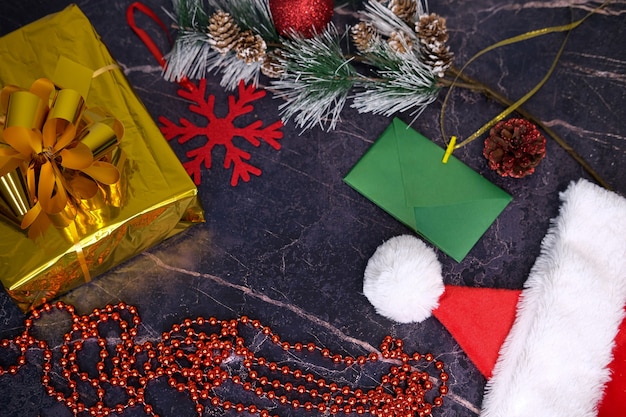 Presentes de Natal e Ano Novo. Foco seletivo. Chapéu de Papai Noel, caixas com presentes, miçangas, brinquedos de Natal em um fundo escuro.