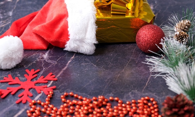 Presentes de Natal e Ano Novo. Foco seletivo. Chapéu de Papai Noel, caixas com presentes, miçangas, brinquedos de Natal em um fundo escuro.