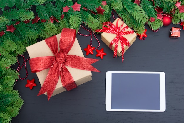 Presentes de Natal em caixas vermelhas na mesa de madeira preta e tablet