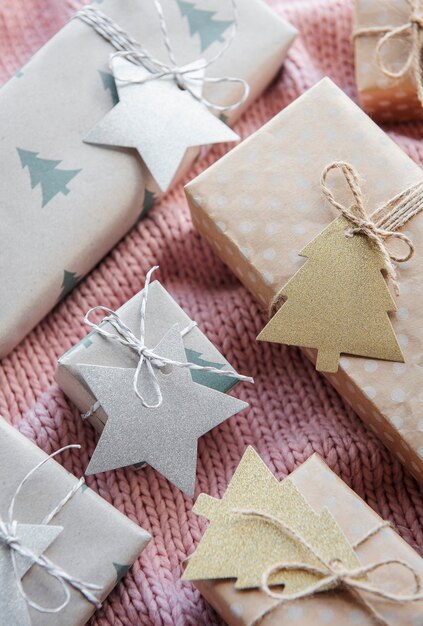 Foto presentes de natal em fundo rosa têxtil de malha. caixas de presente de papel kraft, composição de natal e feliz ano novo. estilo plano, vista de cima