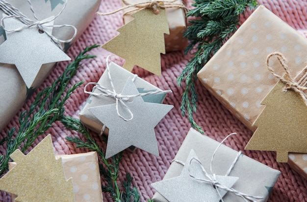 Presentes de Natal em fundo rosa têxtil de malha. Caixas de presente de papel Kraft, composição de Natal e Feliz Ano Novo. Estilo plano, vista de cima