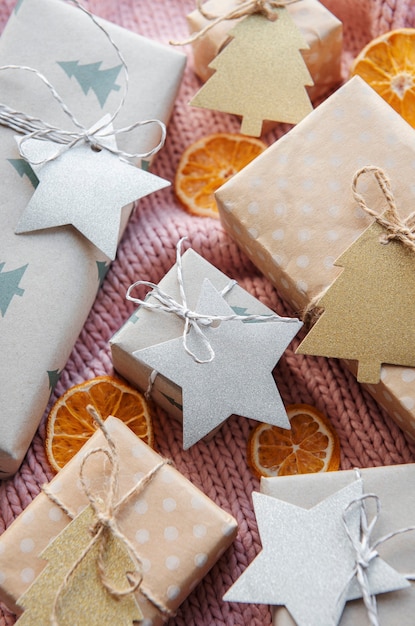 Presentes de Natal em fundo rosa têxtil de malha. Caixas de presente de papel Kraft, composição de Natal e Feliz Ano Novo. Estilo plano, vista de cima