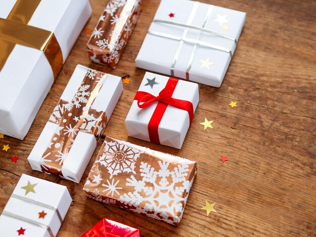 Foto presentes de natal em pano de fundo de madeira presentes em papel dourado branco com confete de estrela cintilante