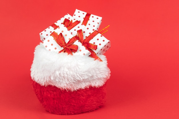 Presentes de natal em saco de papai noel embrulhado em polca de papel de presente em fundo vermelho com espaço de cópia.