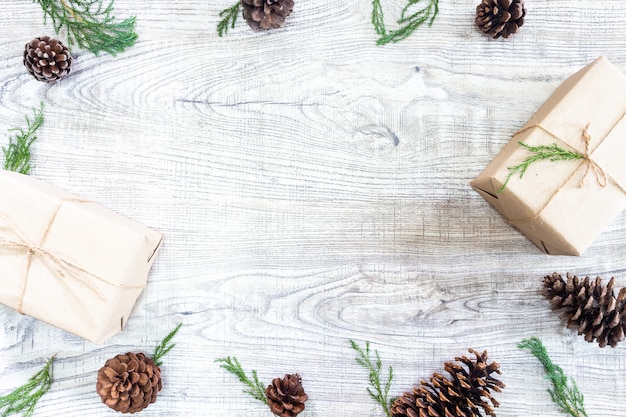 Presentes de natal em um fundo branco de madeira com cones de pinheiro e pinheiro