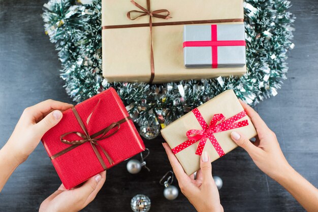 Presentes de natal em uma mesa com preto e mãos segurando presentes