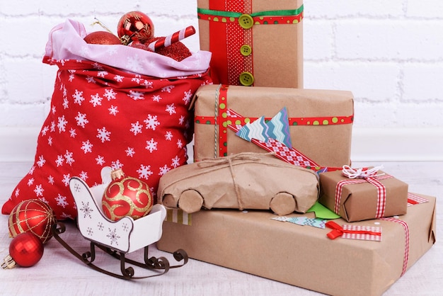 Presentes de Natal feitos à mão e sacola de Natal com bolas no chão do quarto