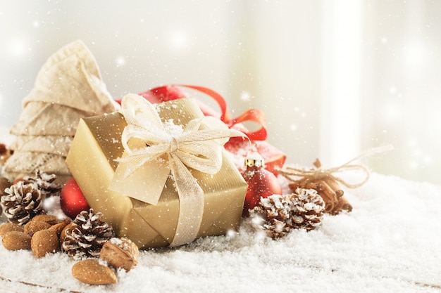 Presentes de natal ou presentes com elegantes decorações de arco e natal no fundo nevado brilhante, conceito de natal