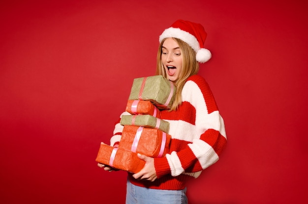 Presentes de Natal. Uma menina com um chapéu de Papai Noel vermelho com presentes de Natal