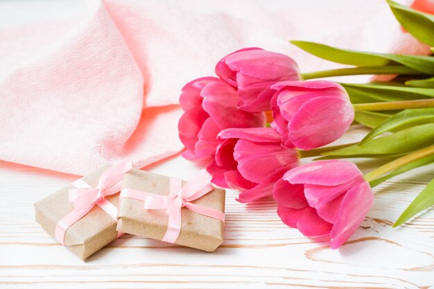 Presentes e buquê de tulipas cor de rosa em cima da mesa