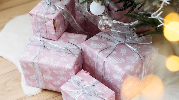 Presentes em embrulho rosa sob a árvore de natal com uma fita de prata natal e ano novo