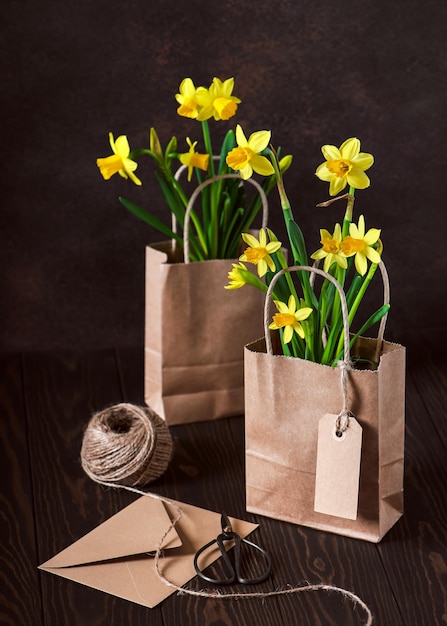 Presentes fáceis com flores de narcisos amarelos florescendo em um artesanato em sacos de papel marrom como um vaso de flores