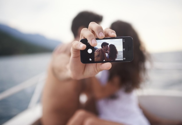 Foto preservando nuestros recuerdos de vacaciones foto de una joven pareja cariñosa haciéndose un autorretrato mientras disfruta de un paseo en bote