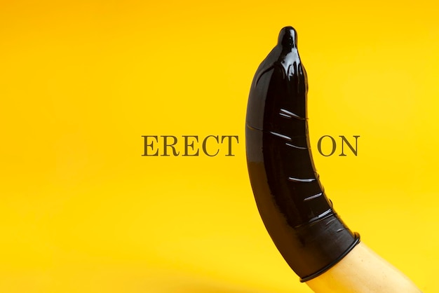 preservativo preto vestido em uma banana em um fundo amarelo conceito de ereção conceito de sexo seguro