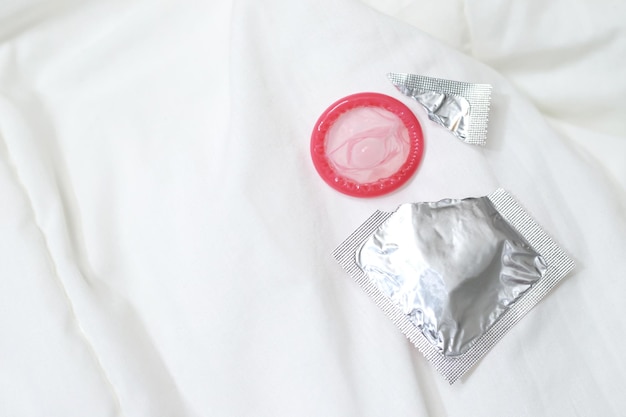 Foto preservativo pronto para uso na mão feminina dar preservativo conceito de sexo seguro na cama prevenir infecção e contraceptivos controlar a taxa de natalidade ou profilática segura dia mundial da sida