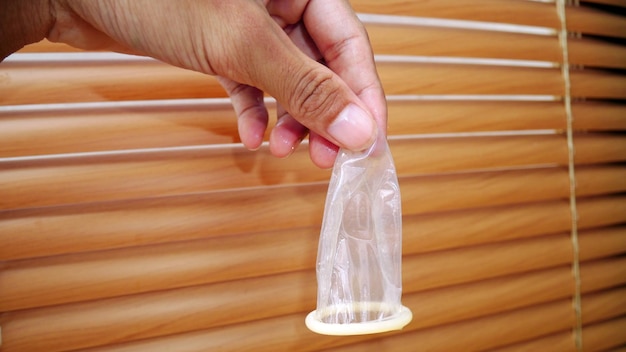 Preservativo usado na mão do homem Os preservativos são usados para proteger contra AIDS e doenças sexualmente transmissíveis