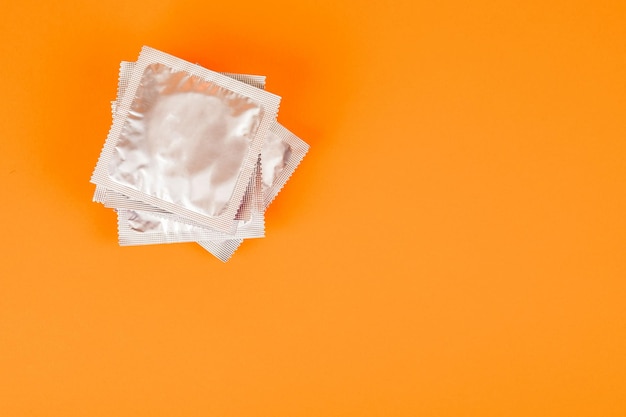 Preservativos em um fundo laranja O conceito de prevenção e sexo seguro