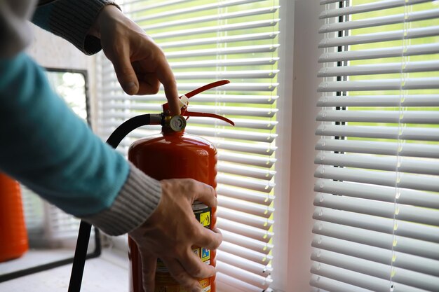 Presiona a mano el gatillo del extintor de incendios disponible en emergencias de incendios antecedentes de daños por conflagración Seguridad