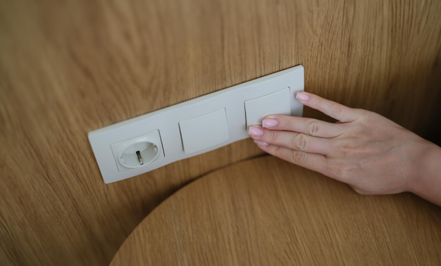 Presionando a mano el interruptor de la luz en la pared de una casa de primer plano