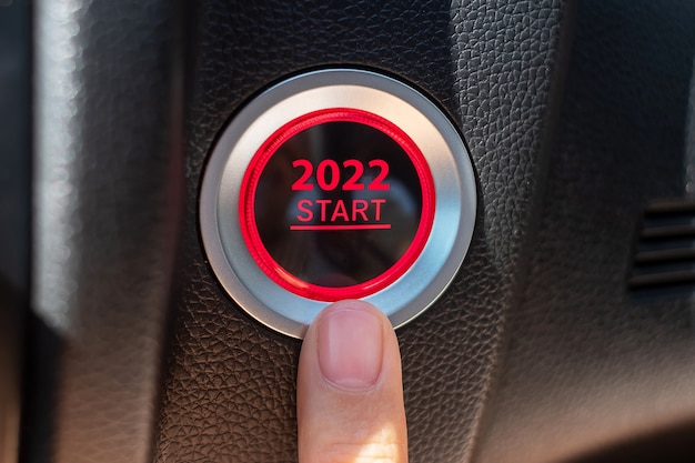 Presione con el dedo el botón de encendido de un automóvil con el texto INICIO 2022