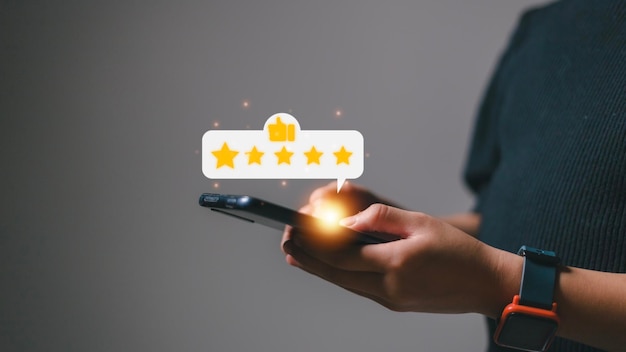 Pressionando a mão na tela do smartphone com o ícone de feedback de classificação de cinco estrelas em ouro e pressione o nível de classificação excelente para dar o melhor ponto de pontuação para revisar o conceito de negócios de serviços