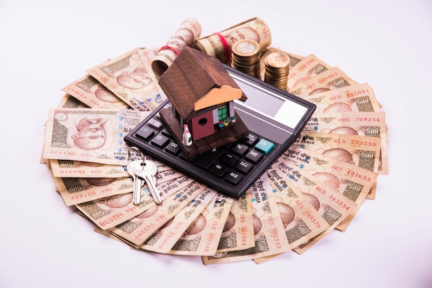 Préstamo o compra de financiación y vivienda en la India: concepto que muestra el modelo de casa en 3D, billetes y calculadora de la moneda india, etc.