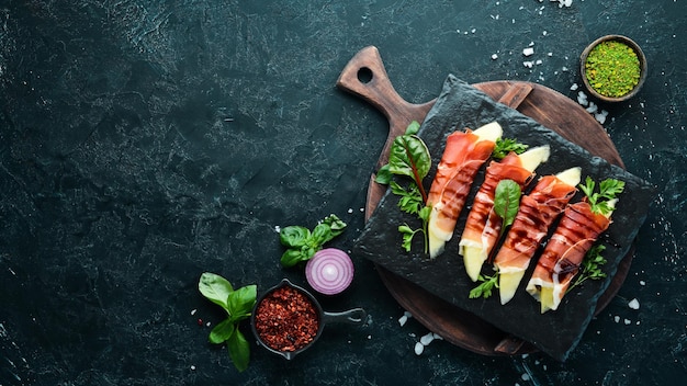 Presunto com melão em um prato de pedra aperitivo italiano tradicional vista superior espaço para cópia grátis