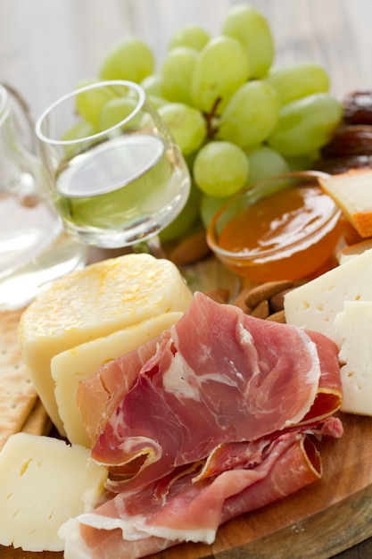 Presunto com queijo e vinho branco na mesa marrom