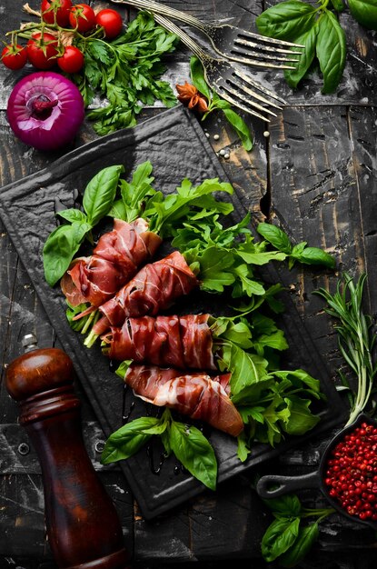 Presunto com rúcula e molho balsâmico em prato de pedra preta Antipasto Vista superior