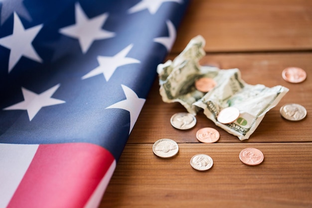 Foto presupuesto, dinero, finanzas, crisis financiera y concepto de nacionalismo: cierre de la bandera americana y monedas de céntimo con billete de dólar arrugado en madera