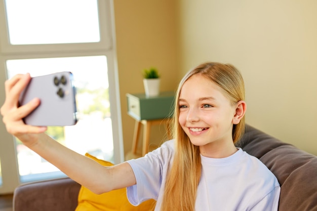 Foto preteen girl macht selfie-fotos auf ihrem smartphone im gemütlichen wohnzimmer zu hause