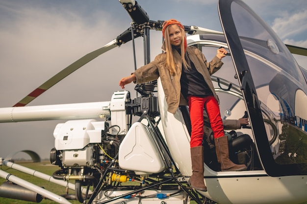 Preteen Mädchen in Fliegermütze stehend im offenen Hubschraubercockpit